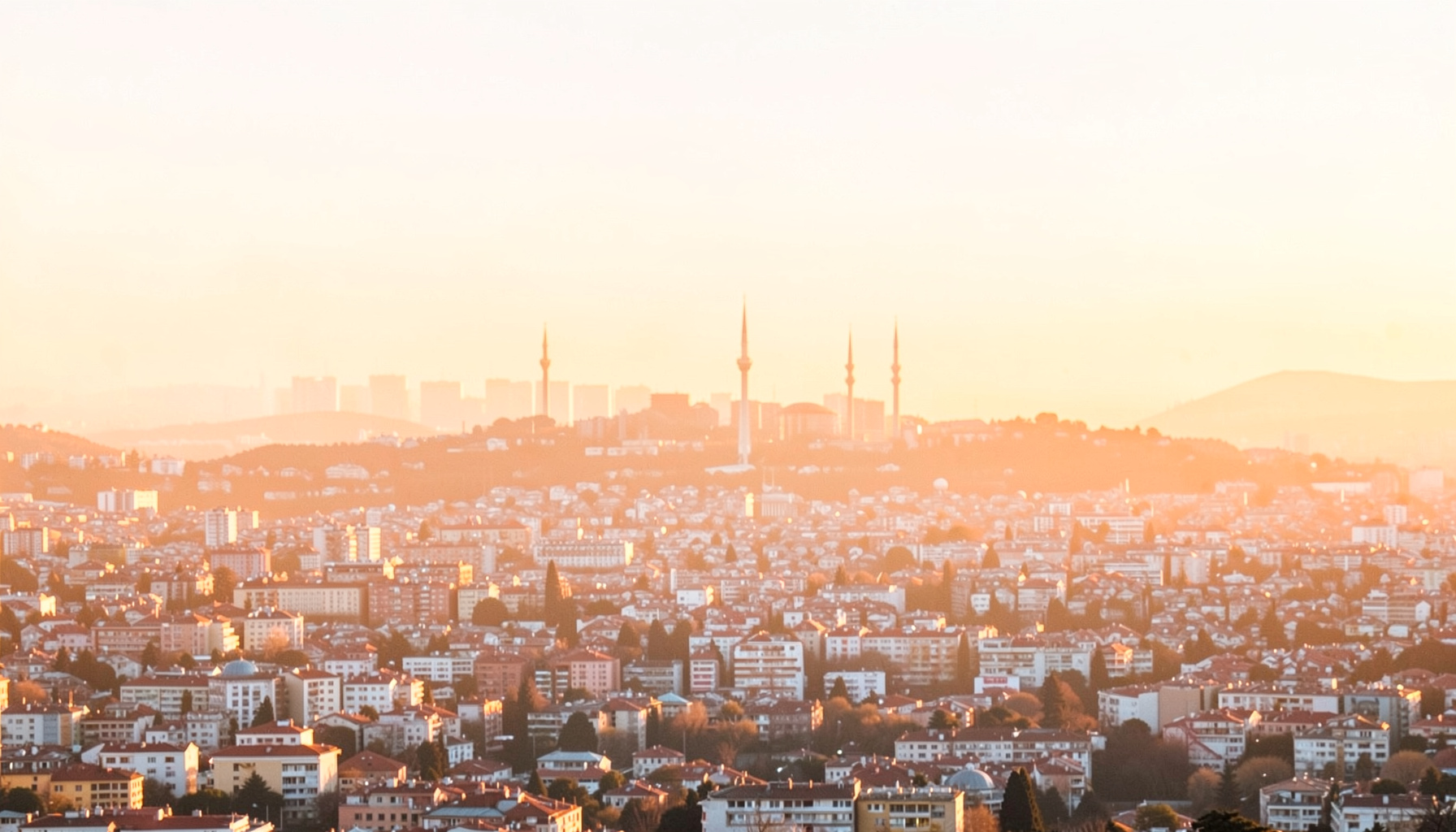 İstanbul silüeti üzerinde sıcak turuncu ve altın tonlarında bir akşam ışığı, şehrin geniş panoramik manzarası