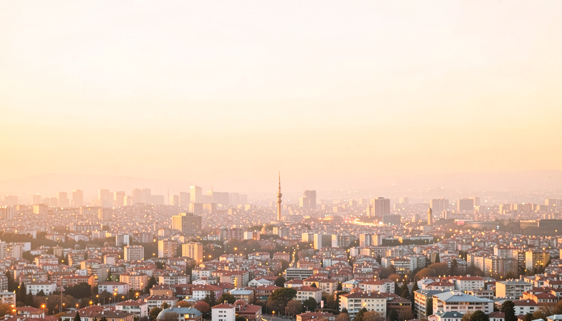 İstanbul silüeti üzerinde sıcak turuncu ve altın tonlarında akşam ışıkları, geniş açılı şehir manzarası