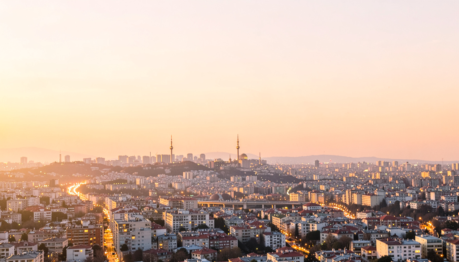 İstanbul silüeti, sıcak akşam ışıklarıyla aydınlanmış şehir manzarası, turuncu ve altın tonlarında gökyüzü